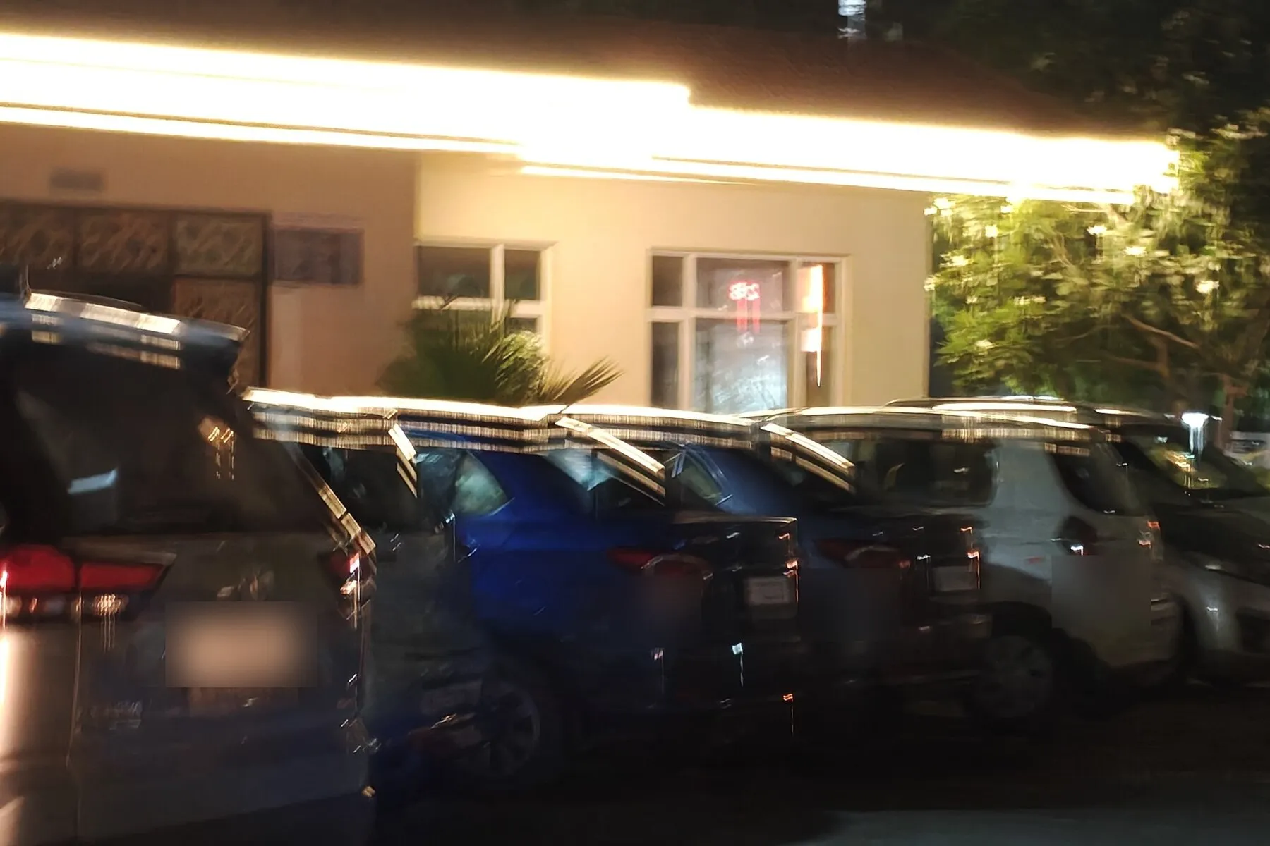 A motion-blurred nighttime photograph of parked cars taken from a moving vehicle
